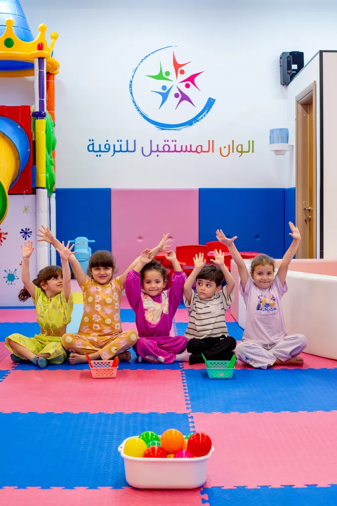 أطفال يرفعون أيديهم فرحًا أمام شعار ألوان المستقبل للترفيه